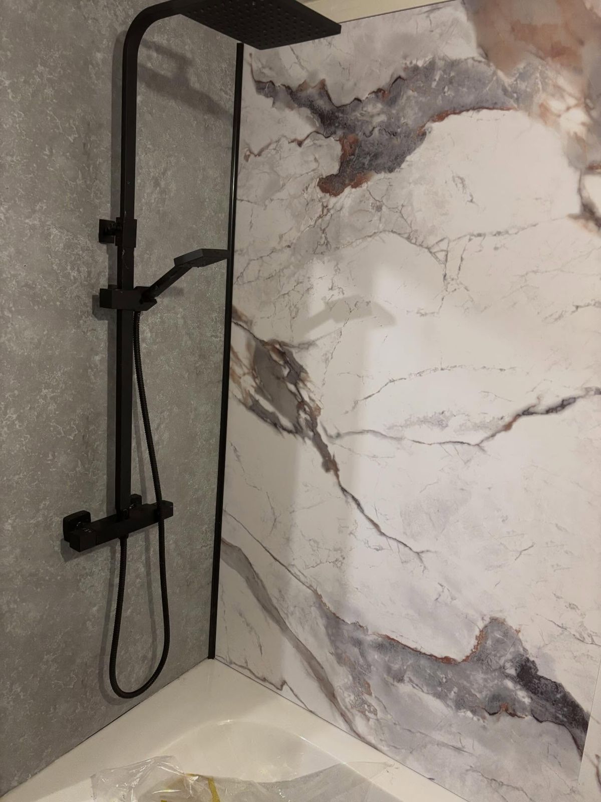 Bold marble panels and a matte black shower system